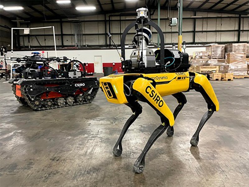 One of team CSIRO's Data61's quadruped robots in the foreground with one of the tracked all terrain robots carrying an aerial robot in the background. (Photo CSIRO)